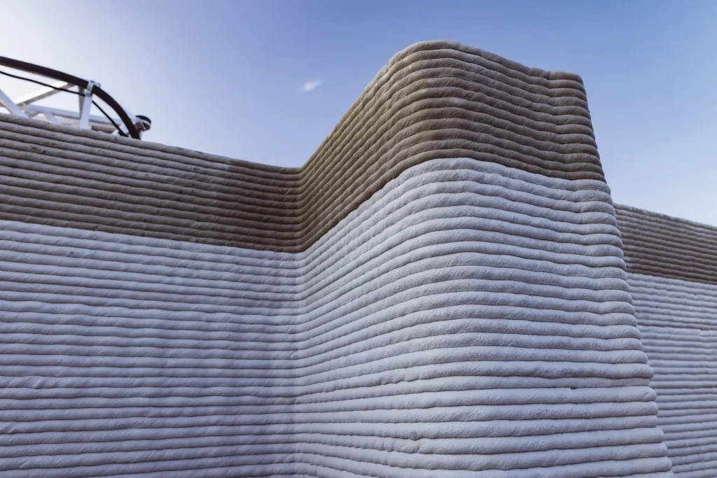A close-up view of a 3D printed concrete wall, showcasing layered construction and material texture.
